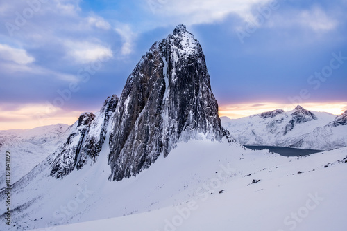 Segla mountain peak seen from Hesten trail near Fjordgard on Senja island, Norway in winter. Scenic winter landscape with snowy mountains range and cold fjord water at sunset photo