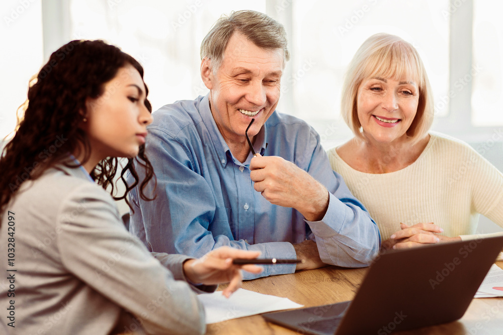 Beautiful Hispanic Travel Agent Working With Clients In Office, Offering Tours To Happy Elderly Couple Beautiful Hispanic Travel Agent Working With Clients In Office, Offering Tours To Happy Elderly Couple