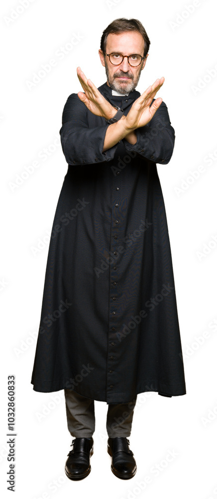 Fototapeta premium Middle age priest man wearing catholic robe Rejection expression crossing arms and palms doing negative sign, angry face