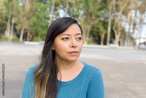 Woman with Long Hair in Teal Shirt Gazing Away. Outdoor Portrait.