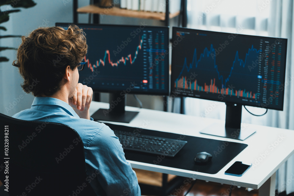 Working young business trader focusing on market stock dynamic graph data in real time two pc screens with back side at modern office. Concept of analyzing dynamic financial exchange rate. Gusher. Working young business trader focusing on market stock dynamic graph data in real time two pc screens with back side at modern office. Concept of analyzing dynamic financial exchange rate. Gusher.