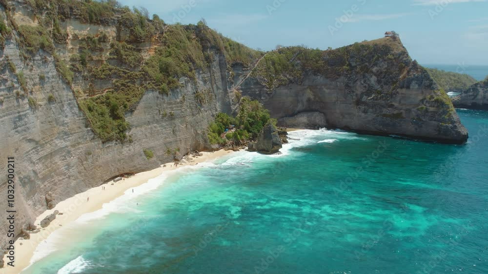 Secluded beach beneath towering cliffs, with turquoise waves crashing against the white sand on a bright sunny day. Secluded beach beneath towering cliffs, with turquoise waves crashing against the white sand on a bright sunny day.