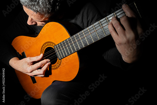 CLOSE UP OF A MAN PLAYING CLASSICAL GUITAR. photo