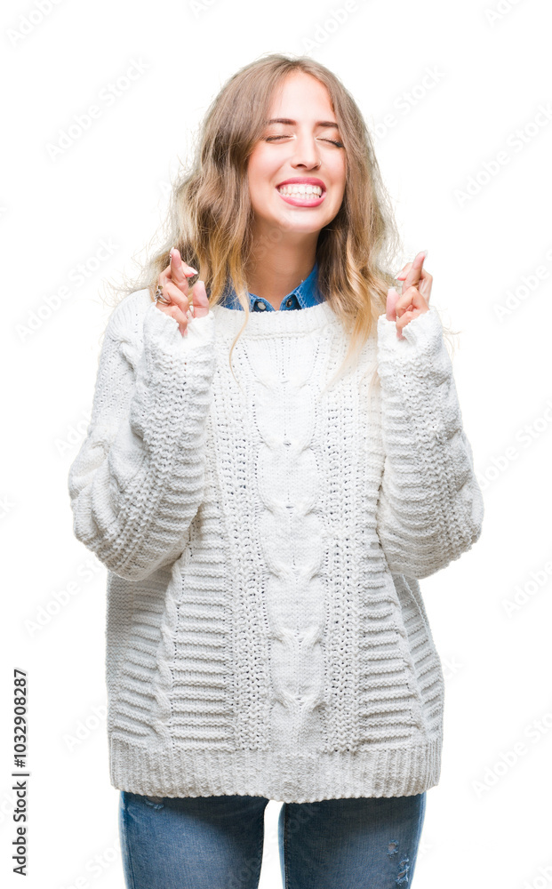 Beautiful young blonde woman wearing winter sweater over isolated background smiling crossing fingers with hope and eyes closed. Luck and superstitious concept. Beautiful young blonde woman wearing winter sweater over isolated background smiling crossing fingers with hope and eyes closed. Luck and superstitious concept.