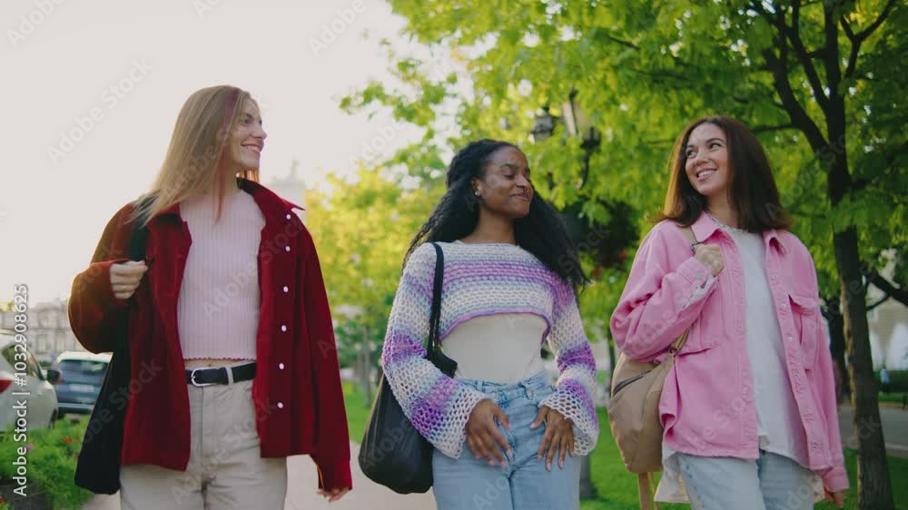 On a sunny day, three women enjoy a leisurely walk in a picturesque park, surrounded by greenery, engaging in joyful conversations filled with laughter and companionship