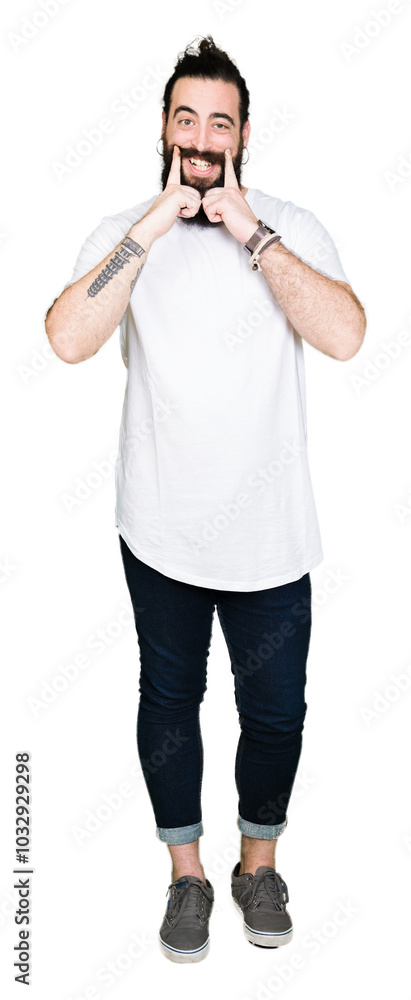 Young hipster man with long hair and beard wearing casual white t-shirt Smiling with open mouth, fingers pointing and forcing cheerful smile Young hipster man with long hair and beard wearing casual white t-shirt Smiling with open mouth, fingers pointing and forcing cheerful smile