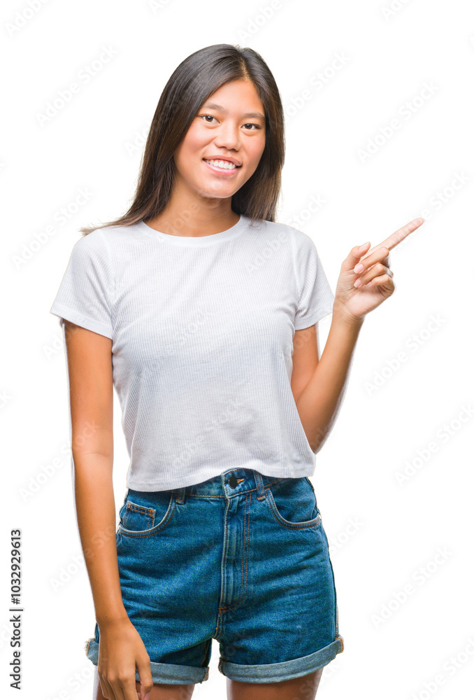 Young asian woman over isolated background with a big smile on face, pointing with hand and finger to the side looking at the camera.