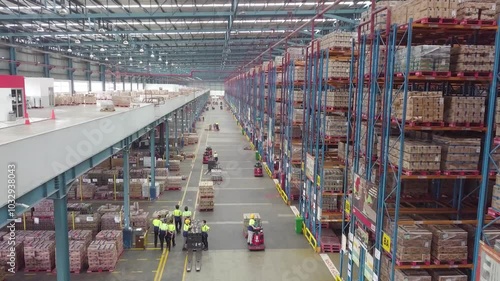 Delivery Warehouse full of shelves with goods in cardboard boxes, workers sort packages, move inventory with pallet trucks and Forklifts. Product Distribution Logistics Center. Asia.
