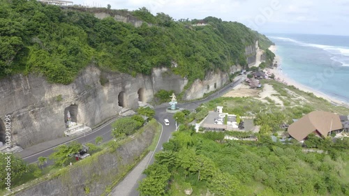 Beautiful coastline beach with a white lighthouse, roads and tourist clubs on a sunny day. Aerial landscape of Pandawa Beach, Bali, Indonesia. Bird's-eye view of Ocean landscape.