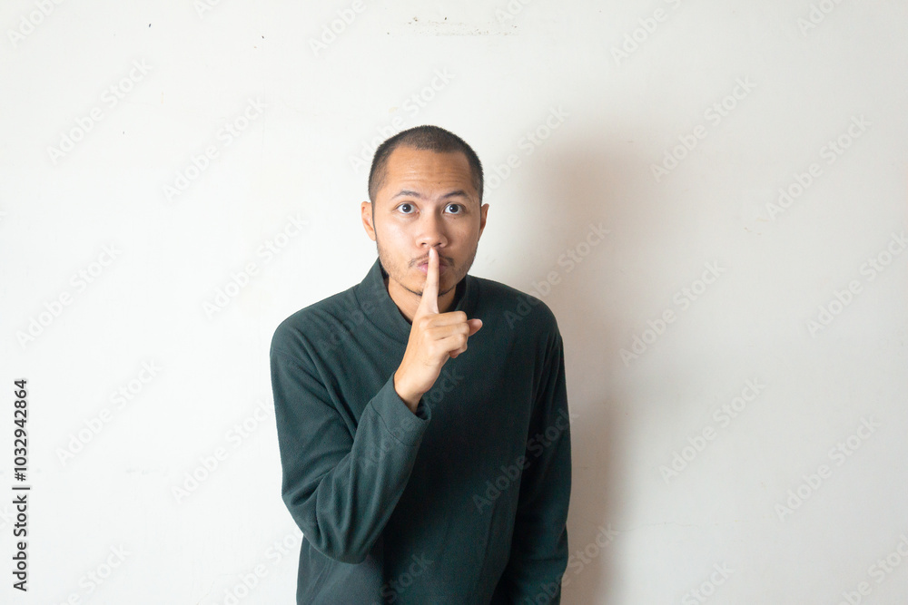 Young men wearing sweater gesturing silent on isolated white background Young men wearing sweater gesturing silent on isolated white background