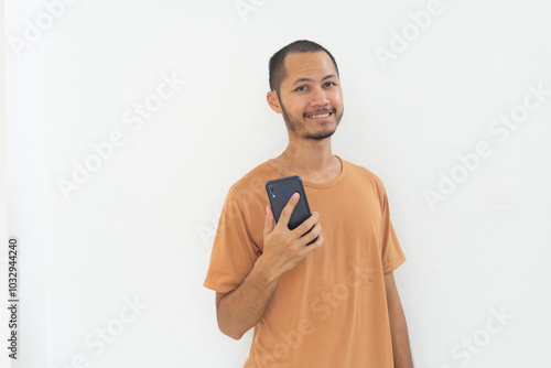 Young men wearing orange shirt is smiling using moble phone on isolated white background photo