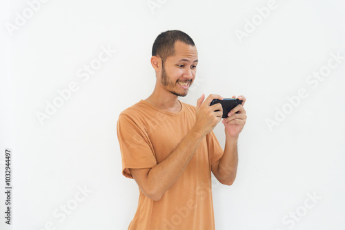 Young men wearing orange shirt is happy playing game using phone on isolated white background photo