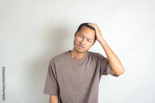 Young men wearing purple shirt is rubbing his head on isolated white background photo