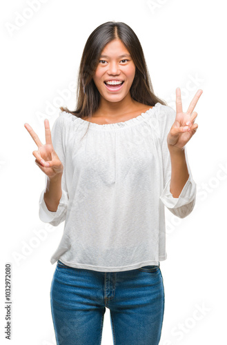 Young asian woman over isolated background smiling looking to the camera showing fingers doing victory sign. Number two.