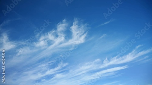 Time lapse of white cirrus clouds moving across a blue sky. Only the sky in the frame.
