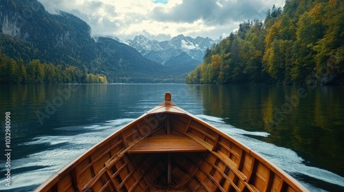 A serene view from the bow of a wooden boat on a tranquil lake, surrounded by mountains and autumn foliage. photo