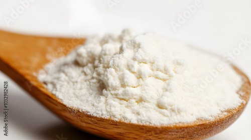 Close-up of tapioca starch or flour powder in wooden spoon on white background. 