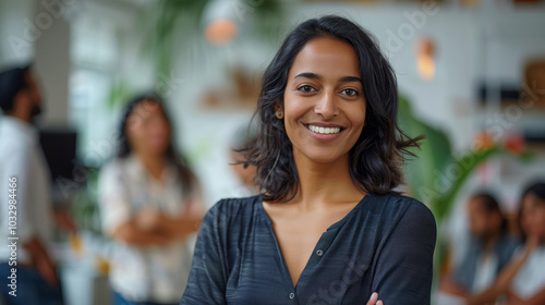 An Indian woman in her late thirties is smiling and standing with a diverse group of Indian men and women who are working together on an office project