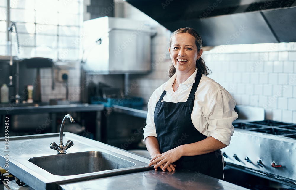 Obraz premium Baker, portrait and happy in cafe kitchen for culinary service, catering and recipe development with apron. Woman, face and smile in bakery for small business, cooking and baking with chef industry
