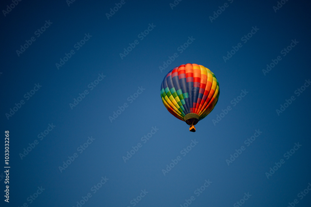 Naklejka premium Colorful hot air balloon with red, green, yellow, purple, orange flying in blue sky with flame burning