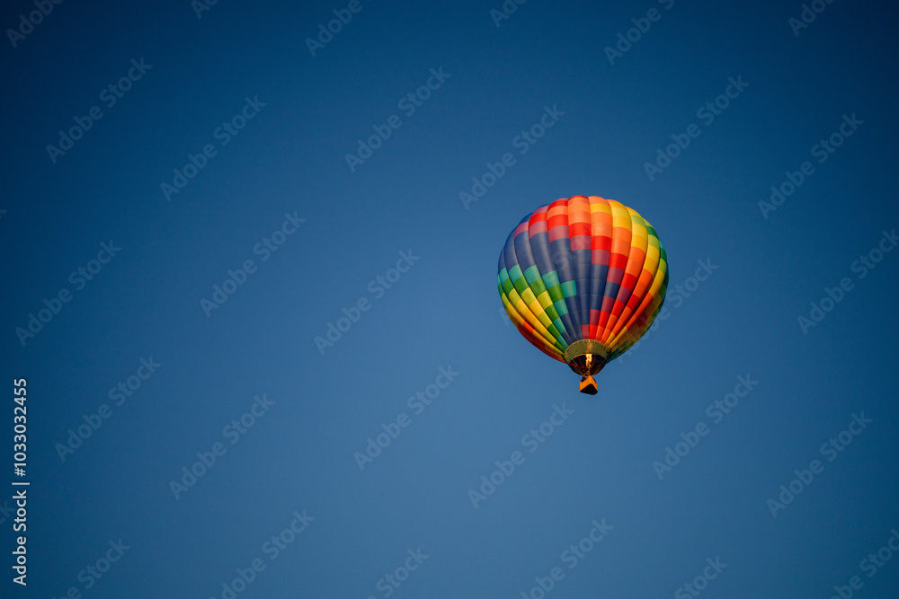 Colorful hot air balloon with red, green, yellow, purple, orange flying in blue sky with flame burning Colorful hot air balloon with red, green, yellow, purple, orange flying in blue sky with flame burning