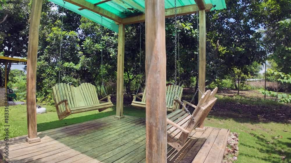 Swing chairs attached by chains to a simple house. Calm and Relaxed Atmosphere in the backyard.