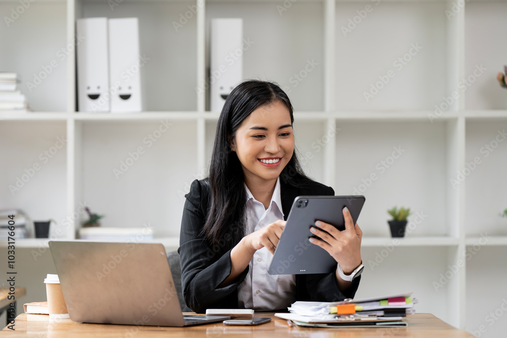 Asian businesswoman CEO holding digital tablet using fintech tab application sitting at workplace in office. Asian businesswoman CEO holding digital tablet using fintech tab application sitting at workplace in office.
