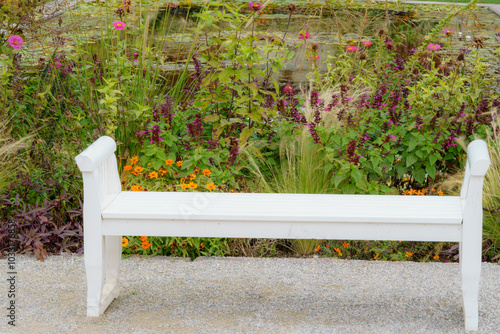 White bench in front of autumnal, colorful perennial meadow and a pond photo