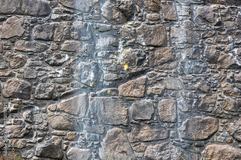 Fototapeta premium Full frame abstract texture background of a rugged medieval stone wall circa 16th century, with copy space