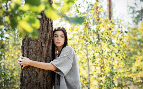 Young woman enjoying a peaceful moment by a tree in a lush green forest during daylight photo