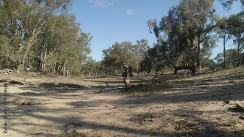 Traditional Australian swagman walks accross a dry river bed in the outback. photo