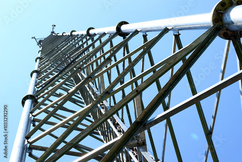This ground-level photograph depicts the intricate steel framework of a telecommunication tower, showcasing its robust construction.