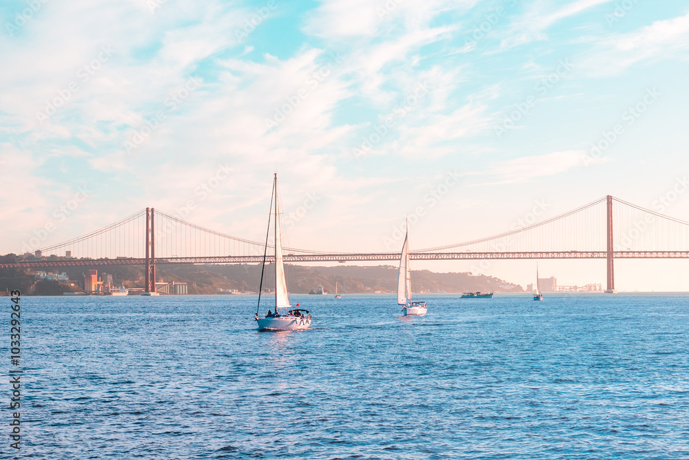 Sailing boats floating on the sea Bay against the backdrop of a large iron bridge, blue sky and sunset Sailing boats floating on the sea Bay against the backdrop of a large iron bridge, blue sky and sunset