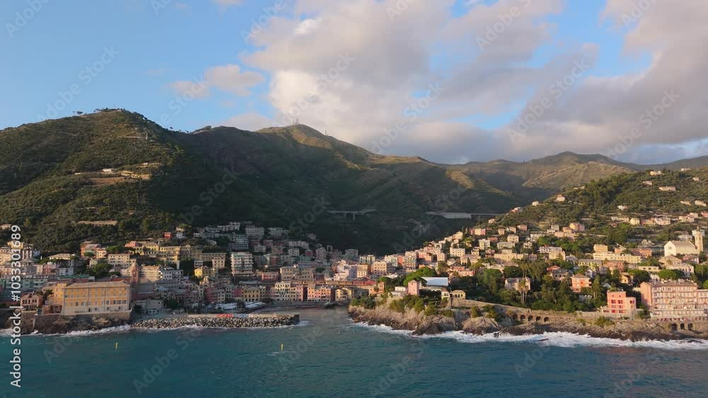 Coastal view of Genoa with colorful houses, a small port, and surrounding mountains at sunset Coastal view of Genoa with colorful houses, a small port, and surrounding mountains at sunset