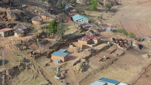 Aerial view of general activity in Basotho rural village. Houses and livestock at foot of hill