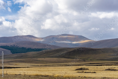 Field with yellow autumn grass in front of a hill. Abuli Mountains, blue sky with clouds in the background photo