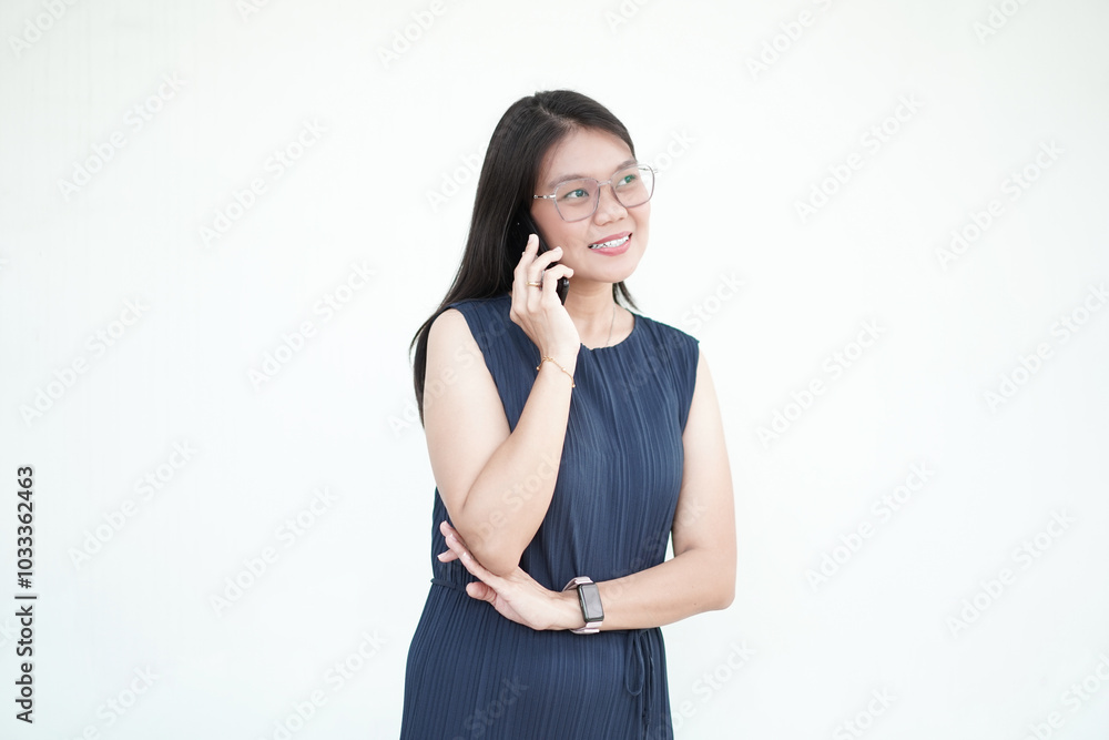 Beautiful Asian woman smiles brightly while making a phone call with her smartphone against a white background Beautiful Asian woman smiles brightly while making a phone call with her smartphone against a white background