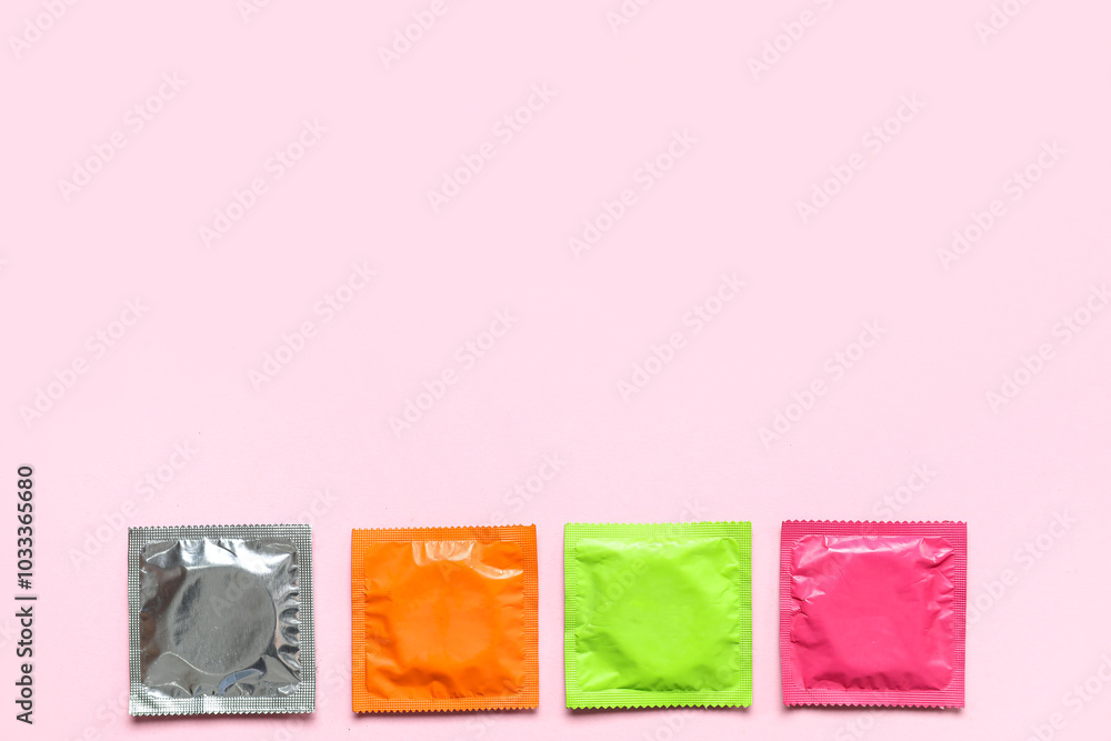 Set of different condoms on pink background Set of different condoms on pink background