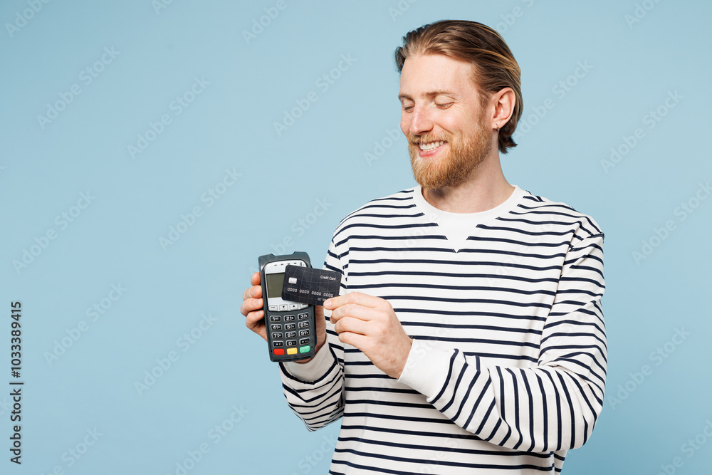Young man he wears striped sweatshirt casual clothes hold wireless modern bank payment terminal to process acquire credit card isolated on plain pastel light blue cyan background. Lifestyle concept. Young man he wears striped sweatshirt casual clothes hold wireless modern bank payment terminal to process acquire credit card isolated on plain pastel light blue cyan background. Lifestyle concept.