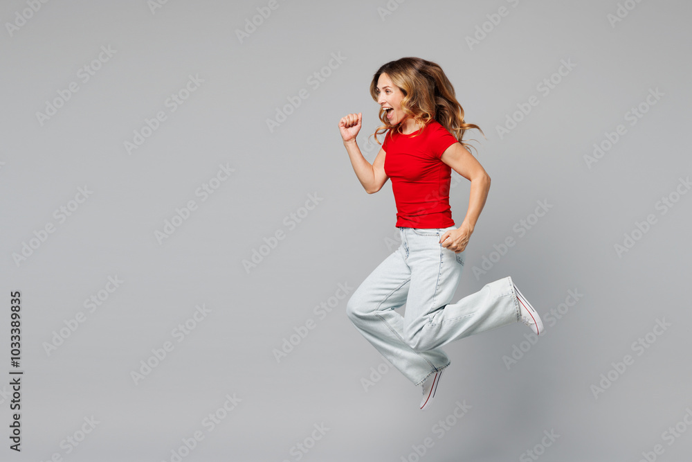 Full body side profile view young excited happy woman she wear red t-shirt casual clothes jump high run fast hurry up, be in rush isolated on plain grey background studio portrait. Lifestyle concept. Full body side profile view young excited happy woman she wear red t-shirt casual clothes jump high run fast hurry up, be in rush isolated on plain grey background studio portrait. Lifestyle concept.