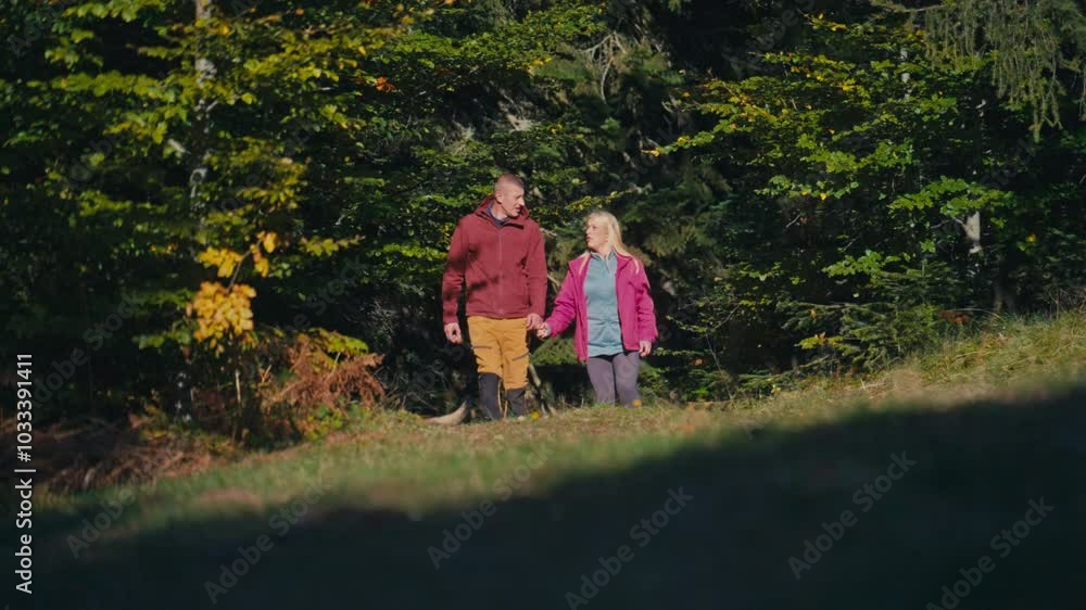 Happy couple in their 40s holding hands and walking out of a lush forest with their dog on a sunny day, enjoying conversation in nature. Concept of companionship, adventure, and love Happy couple in their 40s holding hands and walking out of a lush forest with their dog on a sunny day, enjoying conversation in nature. Concept of companionship, adventure, and love