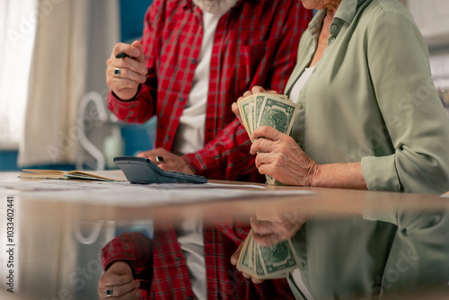 close-up in bright kitchen hands with American bills calculator payment receipts calculator hard pension utilities