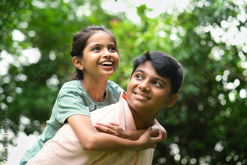 Tableau sur toile Indian big brother giving playful piggyback ride to his little sister outdoors i
