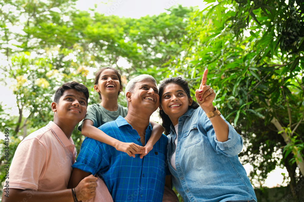 Indian Asian family of four, parents in their forties with two children, in outdoor pointing happily Indian Asian family of four, parents in their forties with two children, in outdoor pointing happily