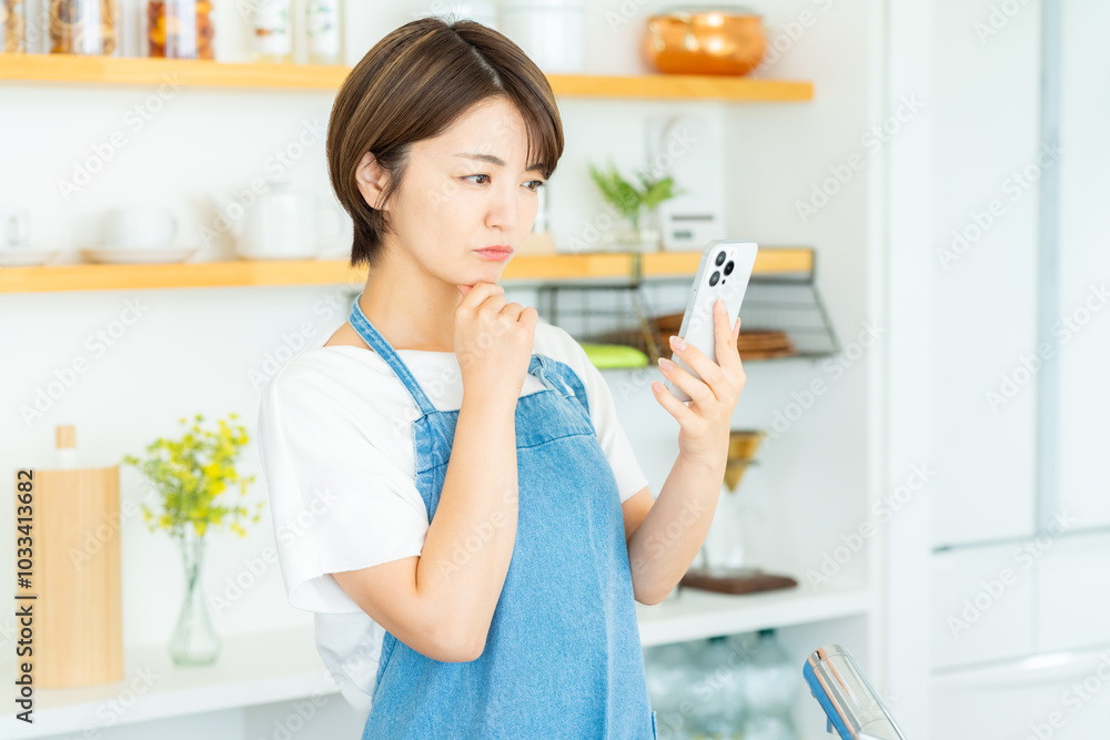 キッチンでスマホを持つ女性 キッチンでスマホを持つ女性