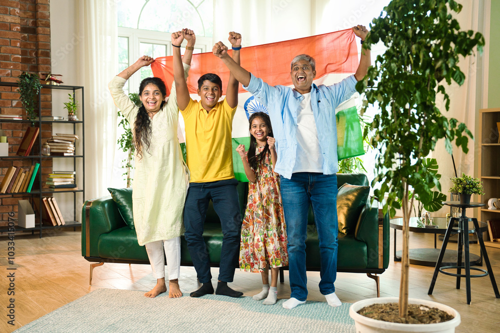 Obraz premium Indian family celebrating victory on TV, waving the tricolor flag joyfully from their sofa