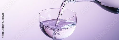 Clear water being poured into a modern designed glass against solid background photo