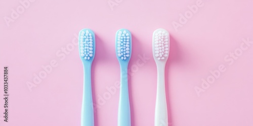 Three plastic toothbrushes on a pastel pink background. Flat lay, top view.