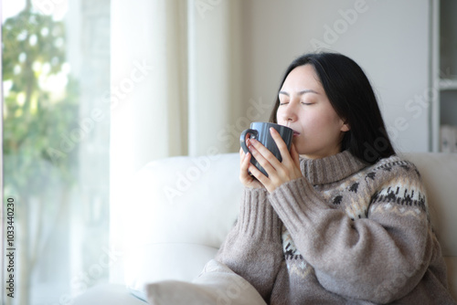 Asian woman in winter drinking hot tea at home