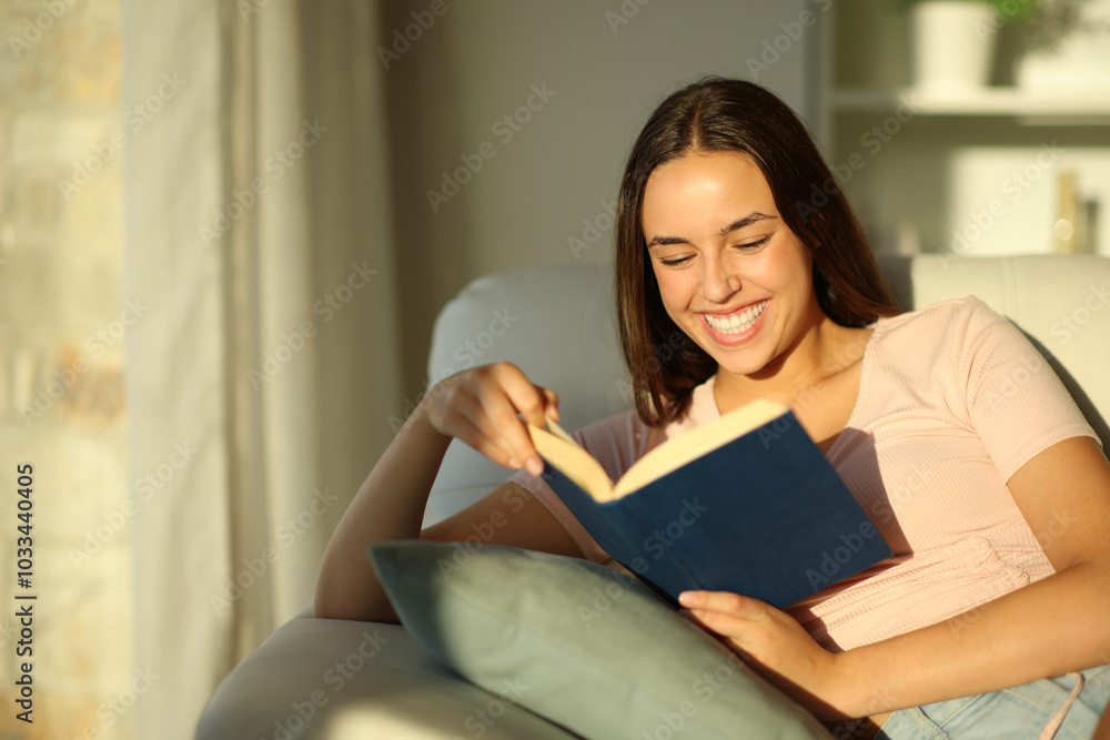 Happy woman reading a paper book sitting on a couch Happy woman reading a paper book sitting on a couch